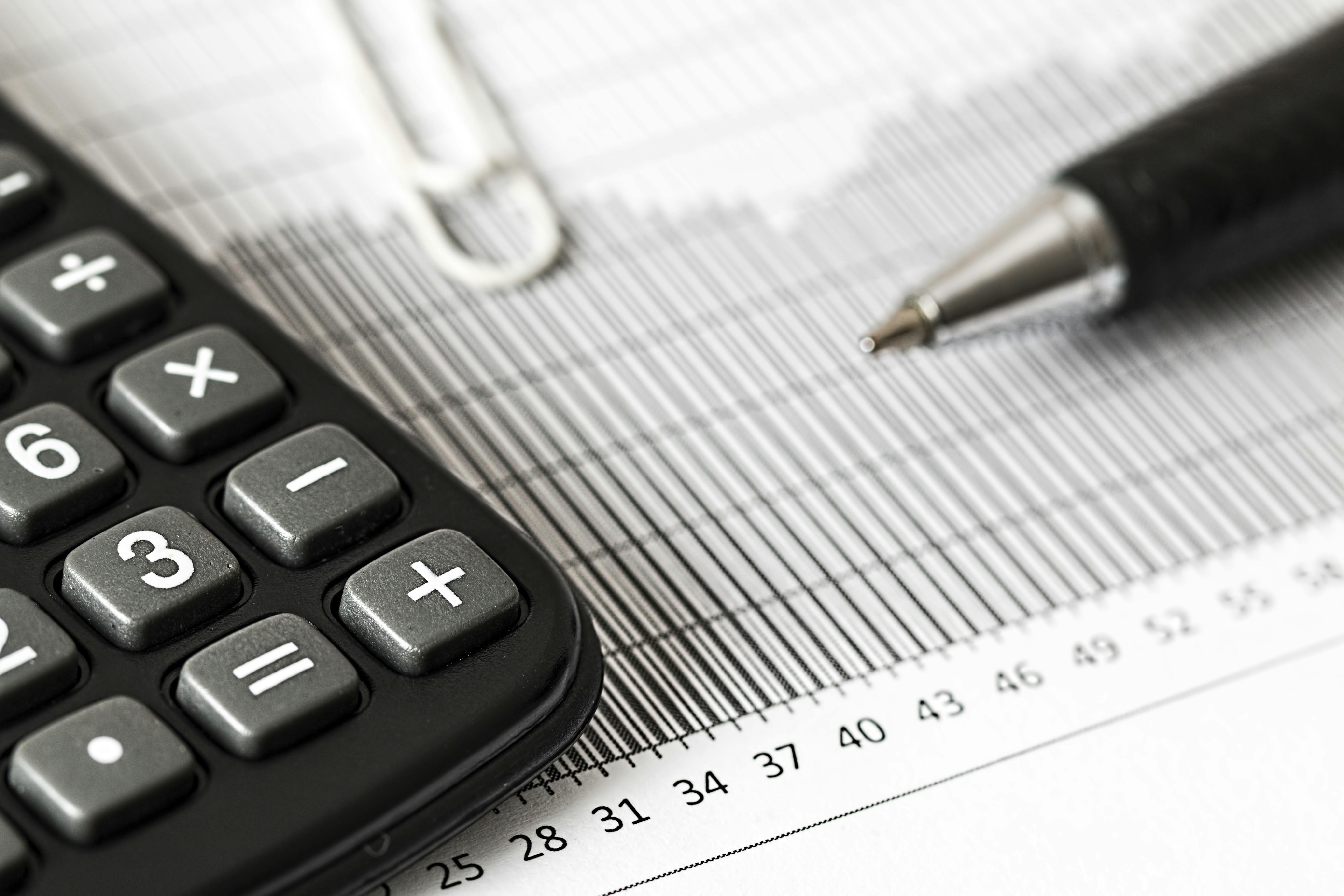 Calculator and pen on a paper sheet | Source: Pexels