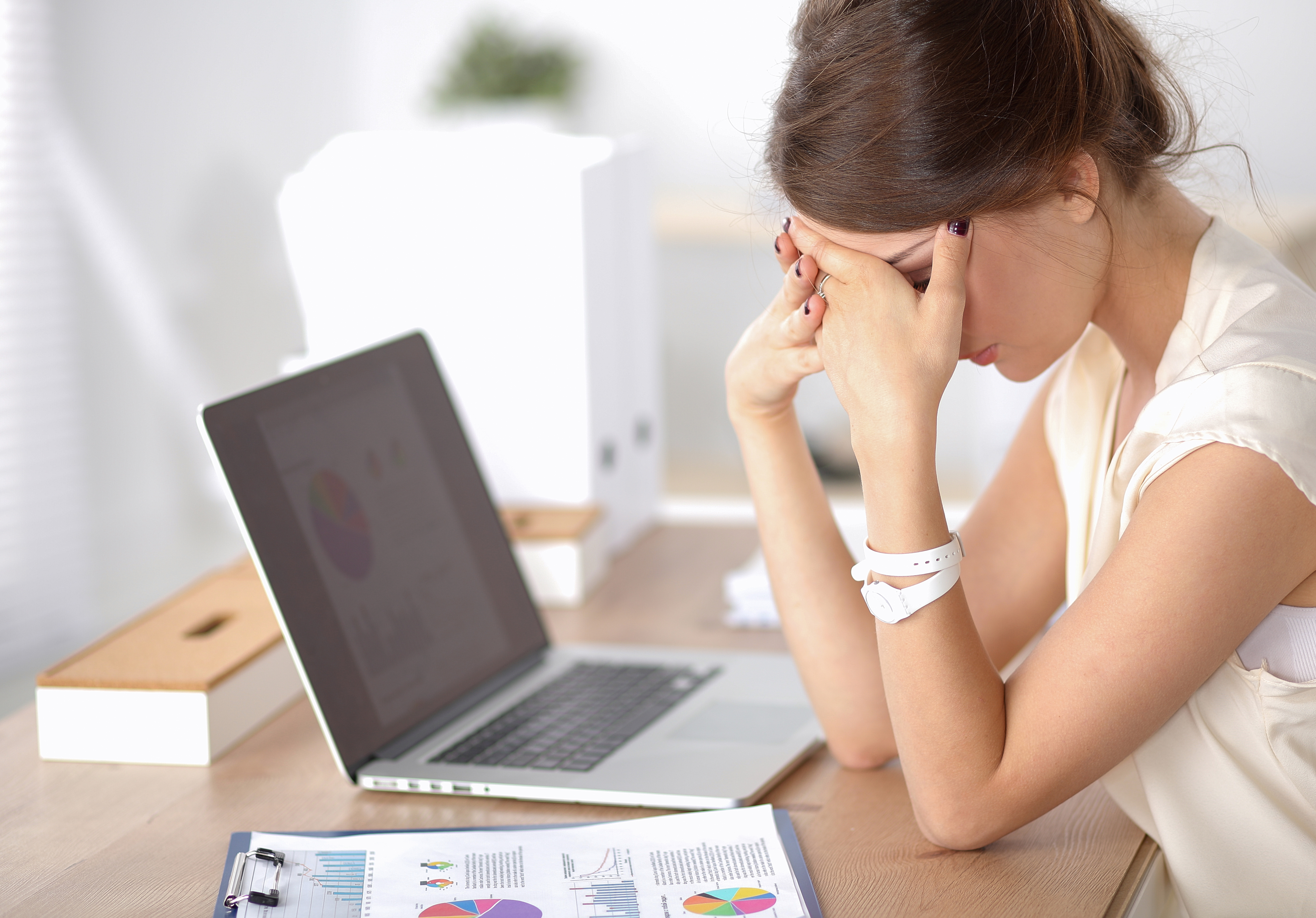 A woman hiding her face while sitting in front of her laptop | Source: Shutterstock