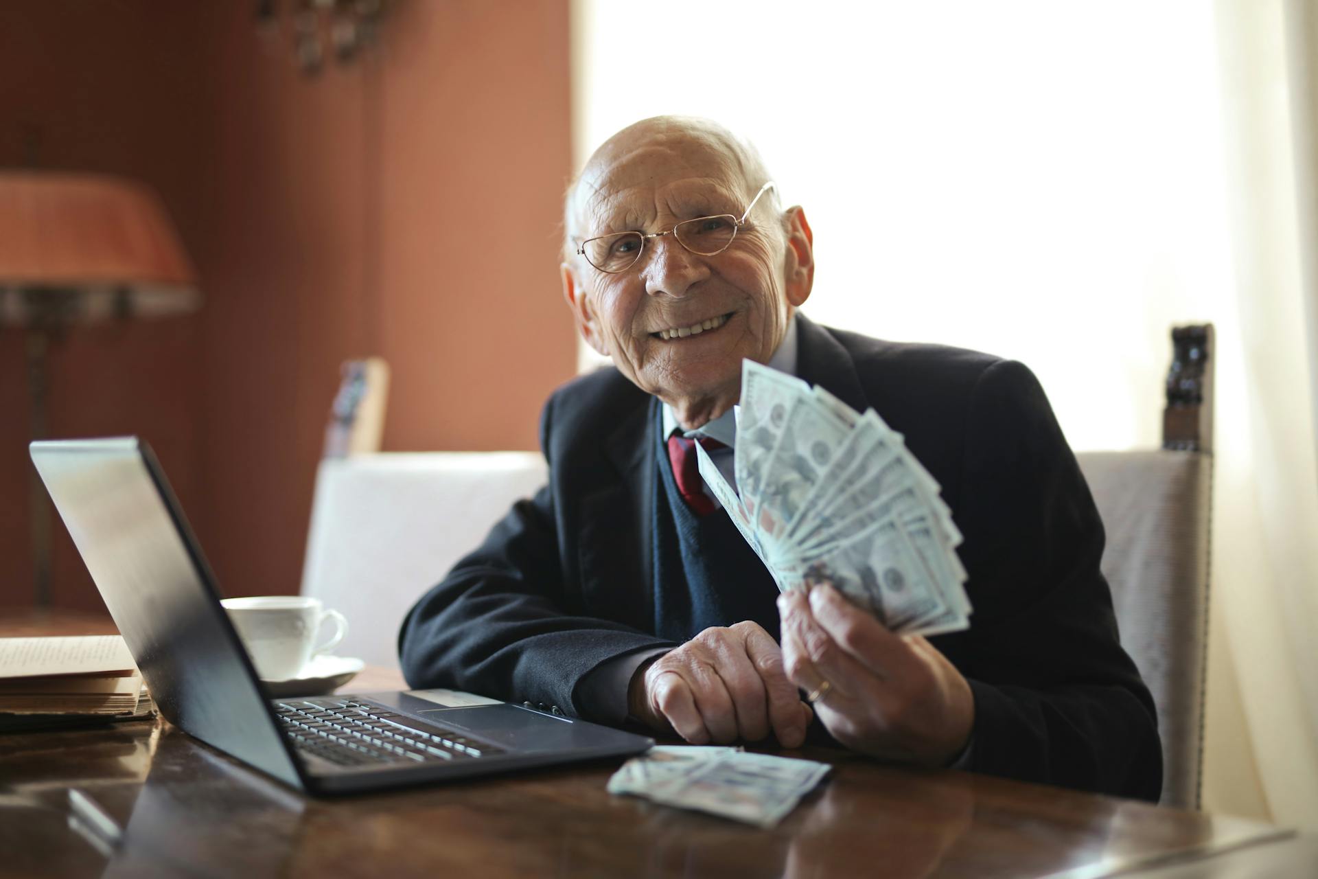 Man smiling and holding cash | Source: Pexels