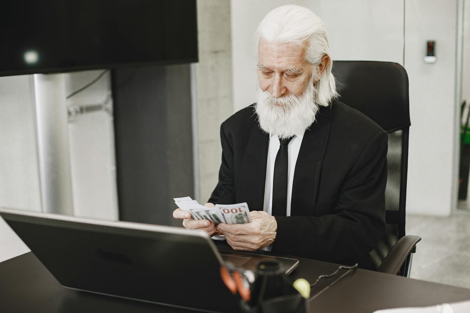 Man counting cash in front of a computer | Source: Pexels