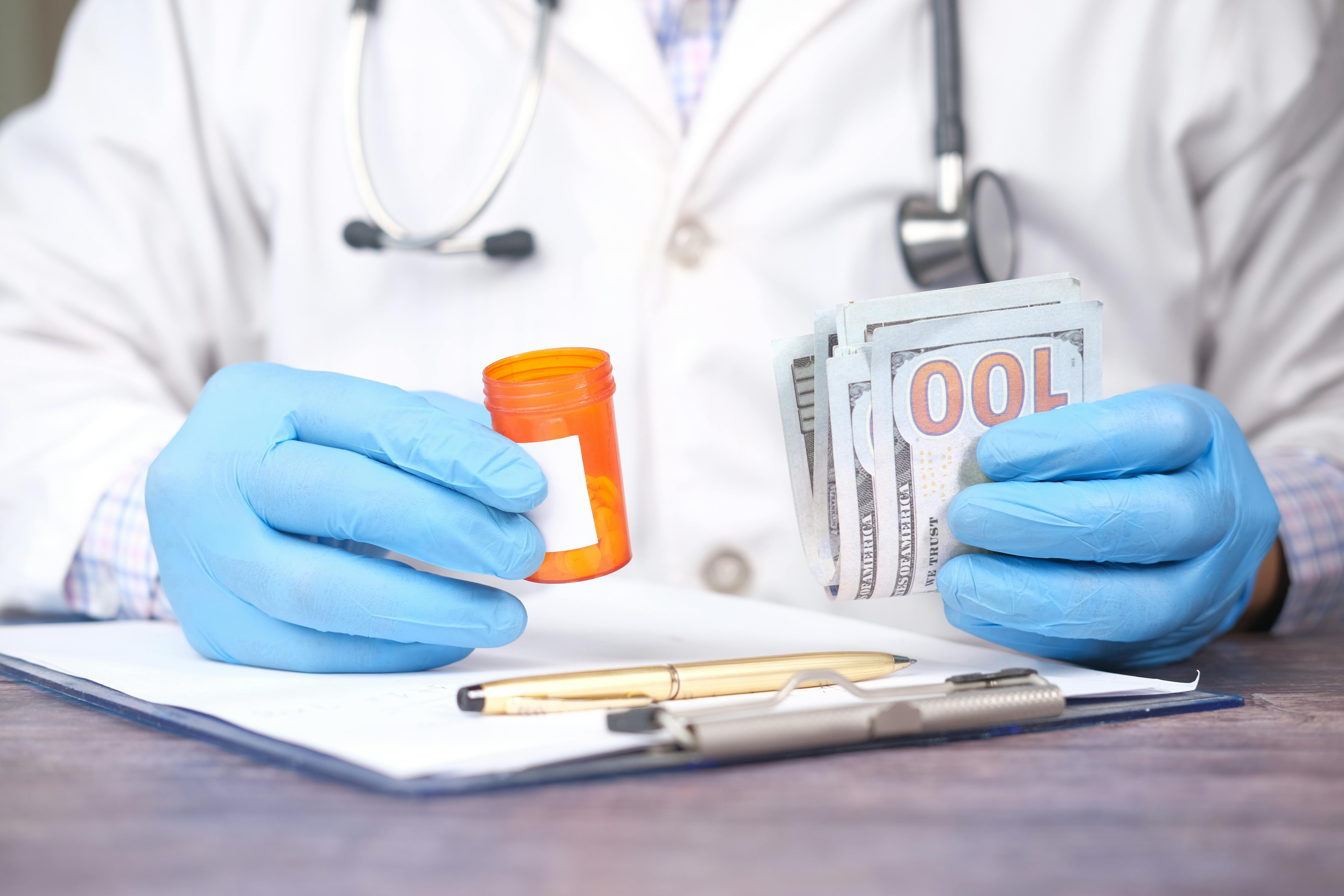 Doctor holding money and a pill bottle | Source: Pexels