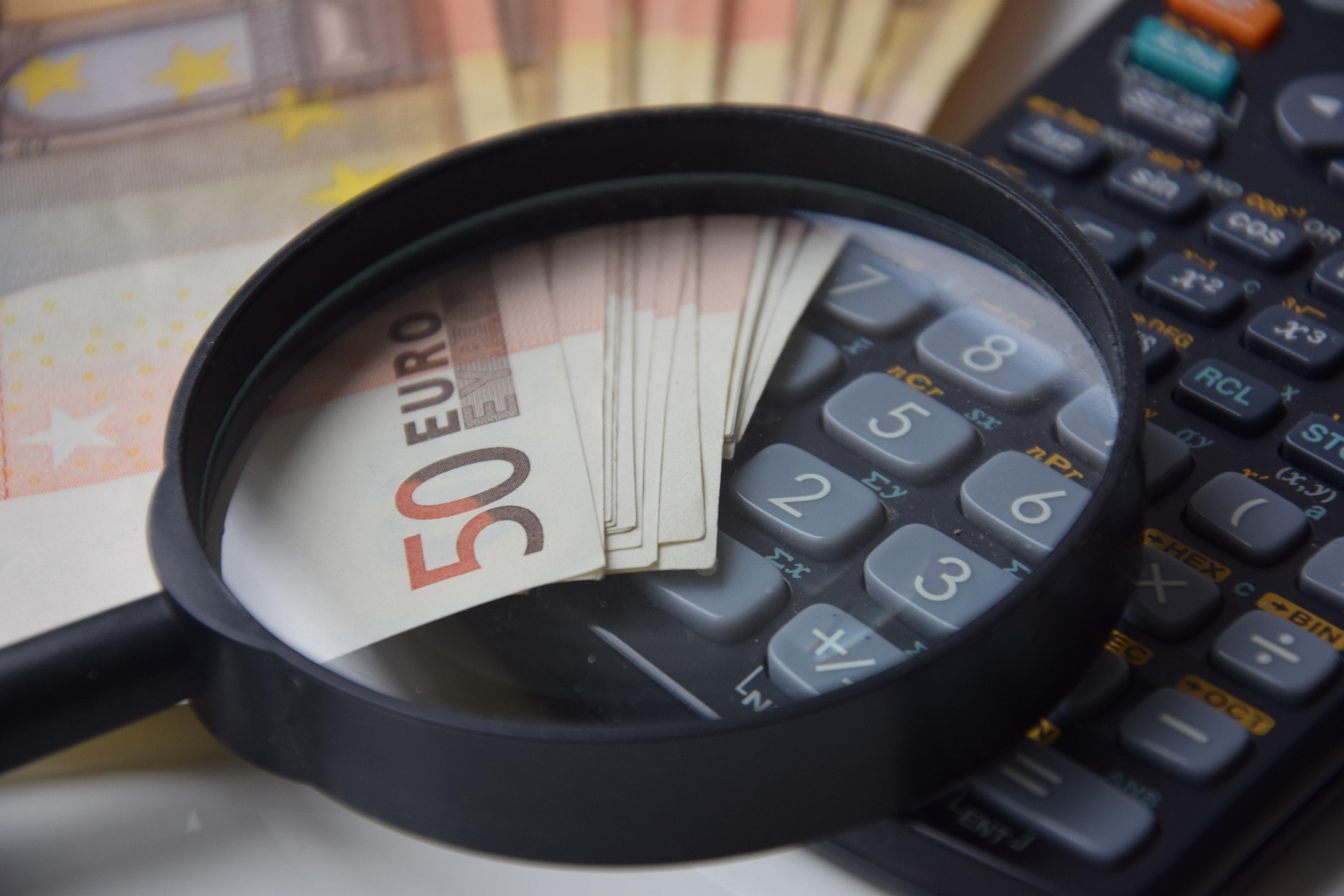 Money, a calculator and a magnifying glass | Source: Pixabay