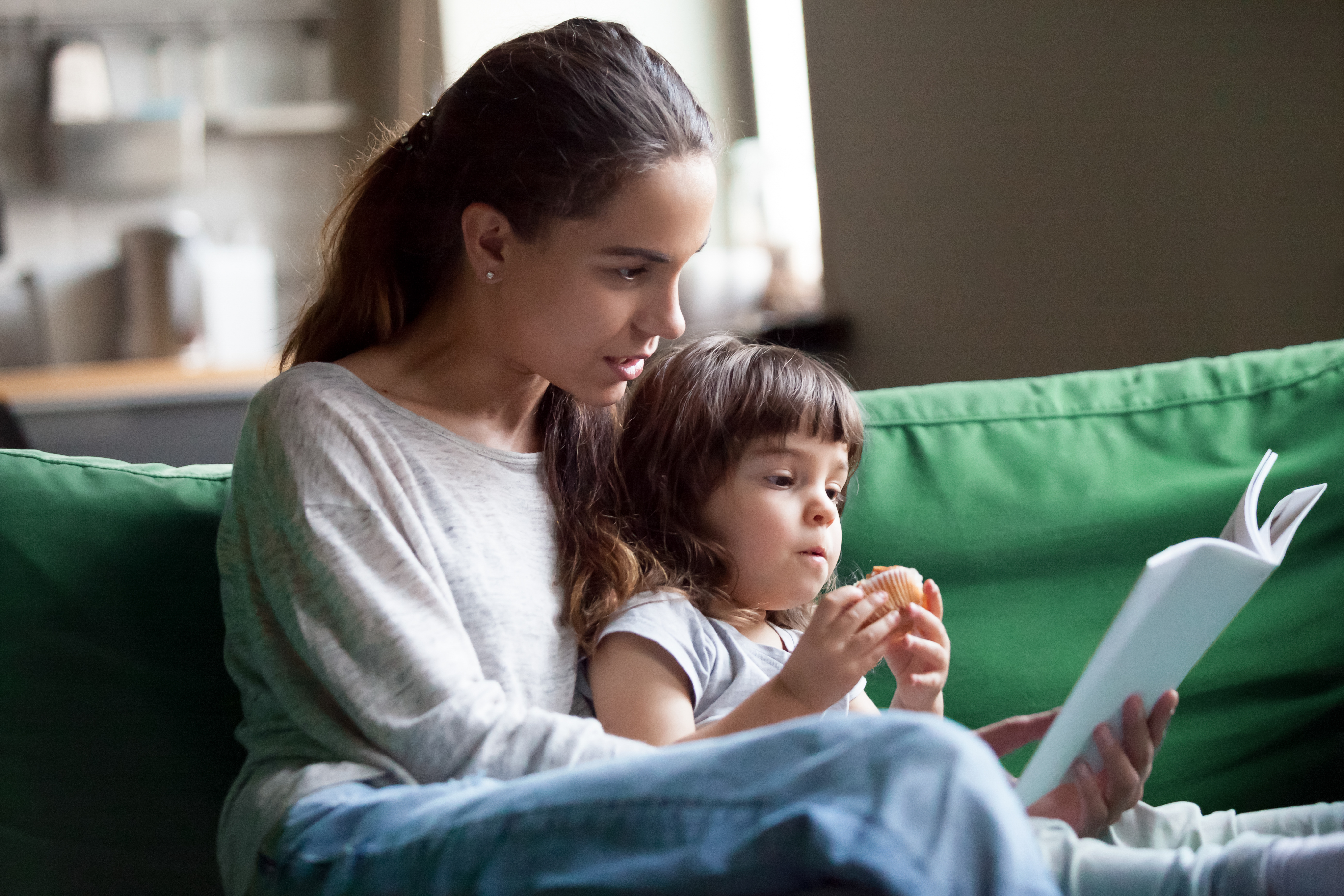 A young woman reading a book with a girl | Source: Shutterstock