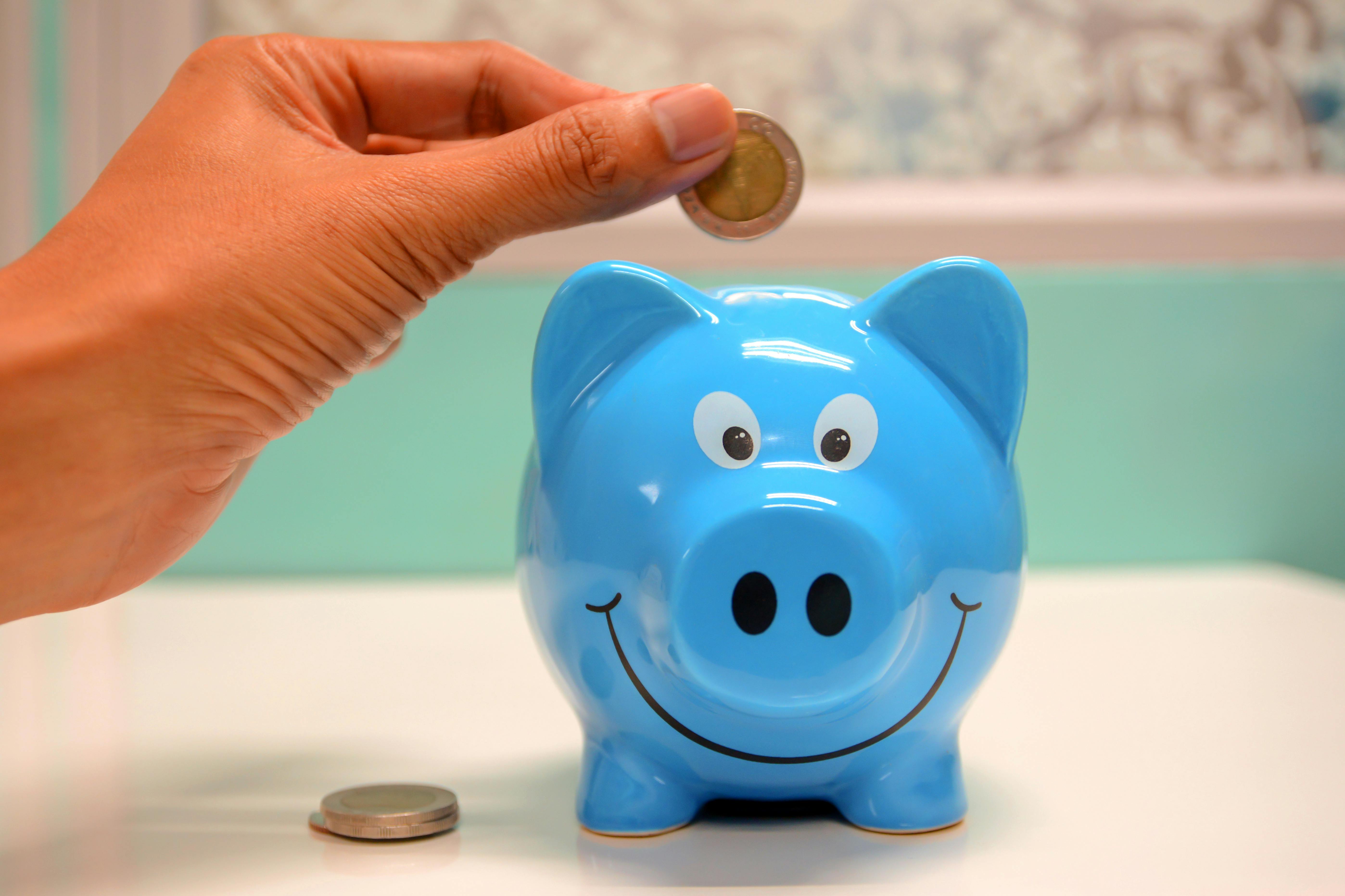 A man puts a coin into a piggy bank | Source: Pexels