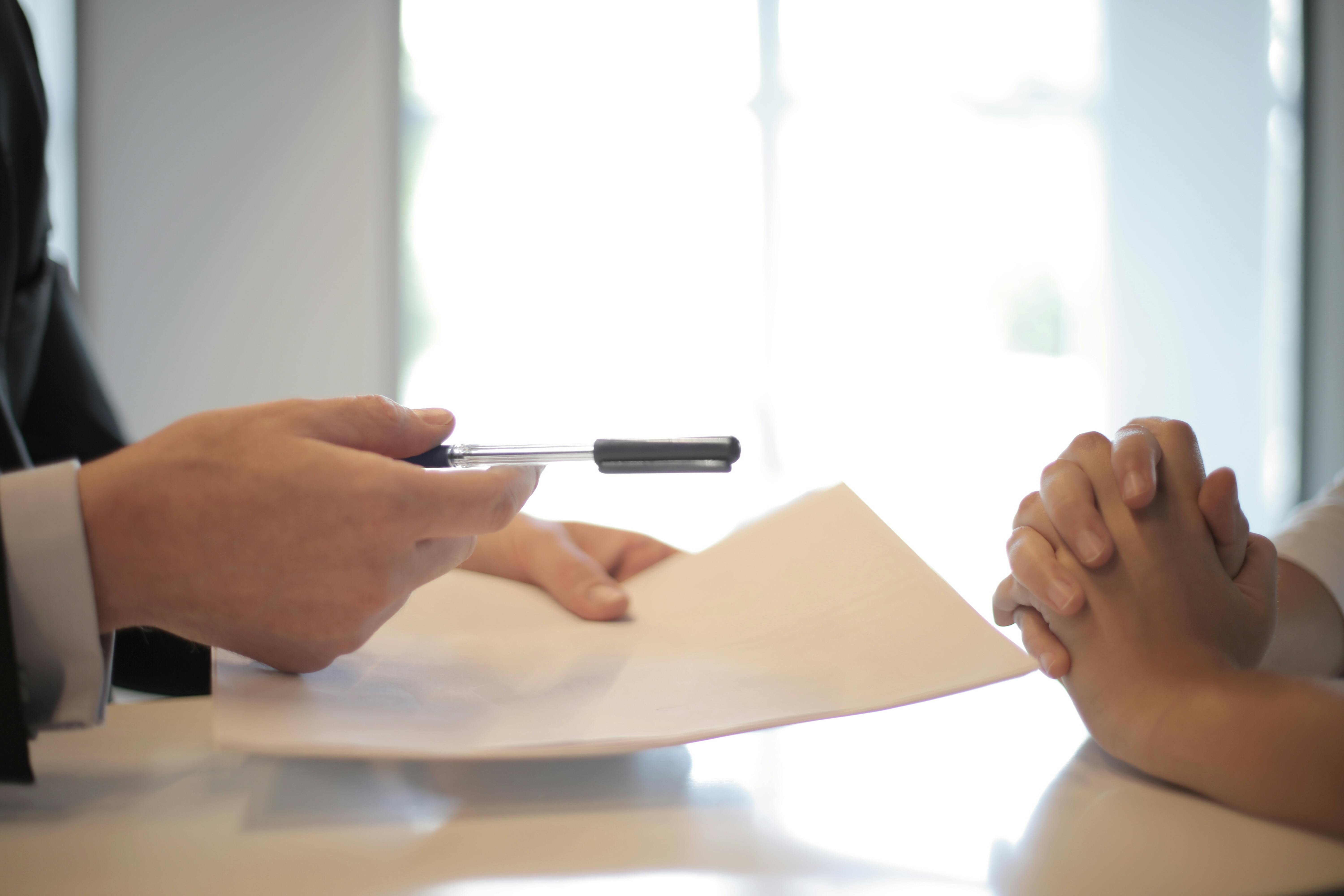 Pen and sheet of paper in hands | Source: Pexels