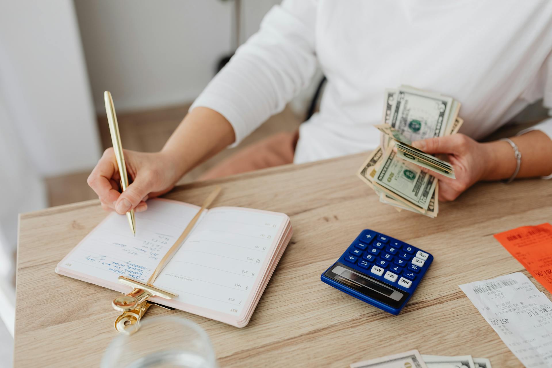 Man holding money and writing in a notebook | Source: Pexels