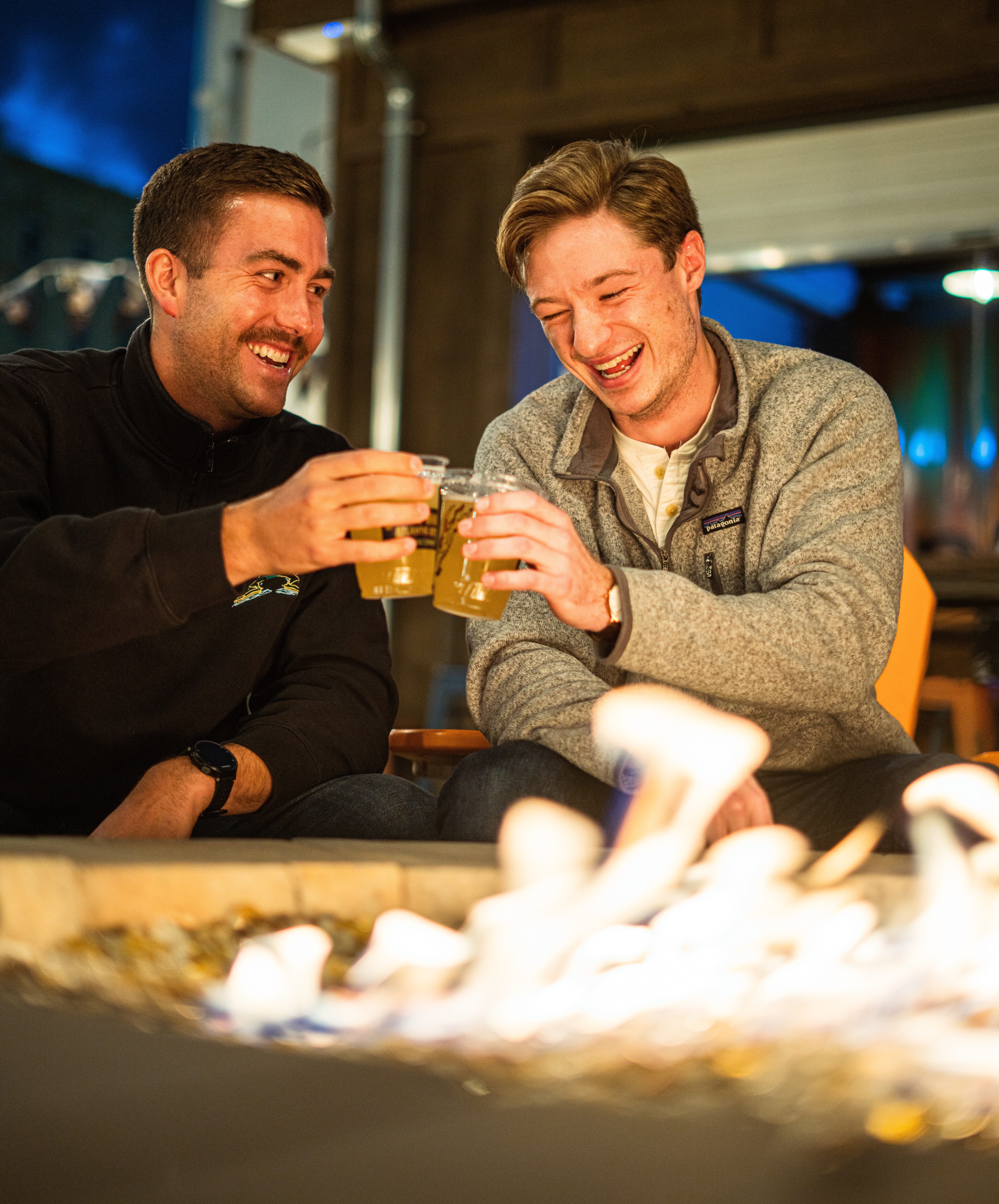 Two people enjoying drinks by the bonfire. | Source: Unsplash