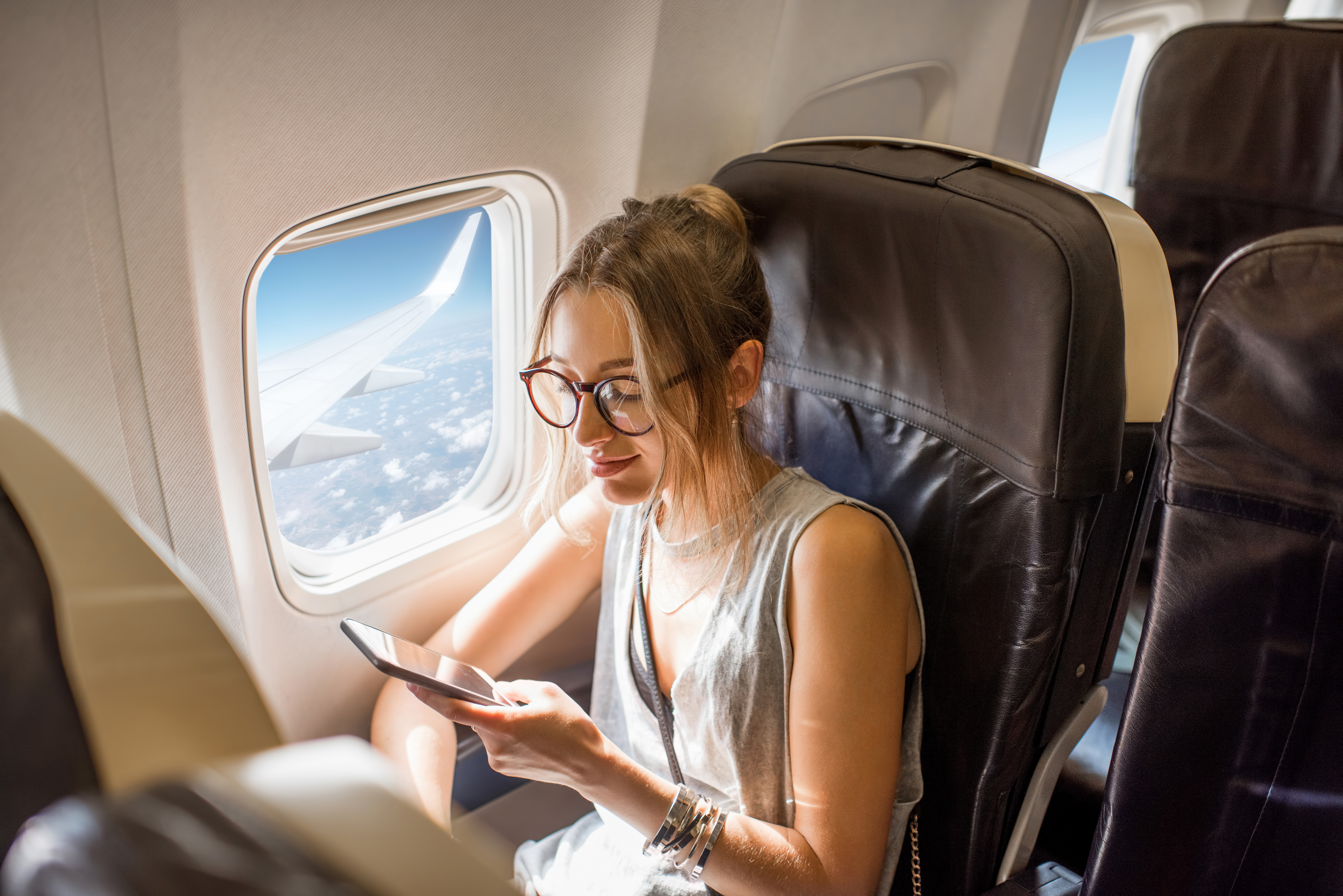 A woman using her phone in an airplane | Source: Shutterstock